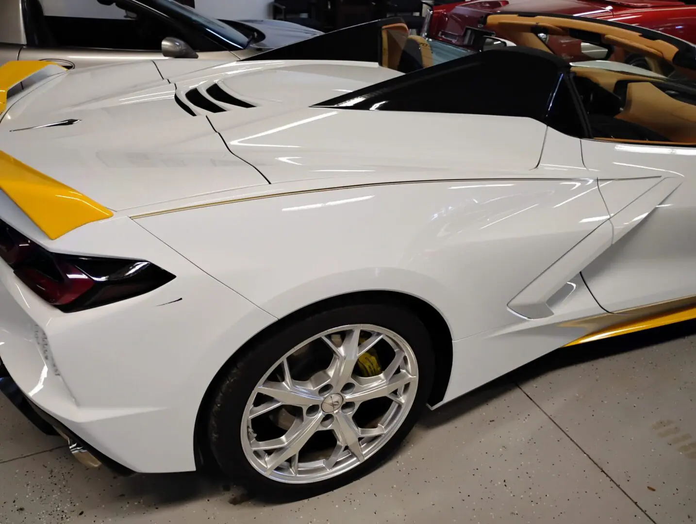 White sports car with yellow accents, indoors.
