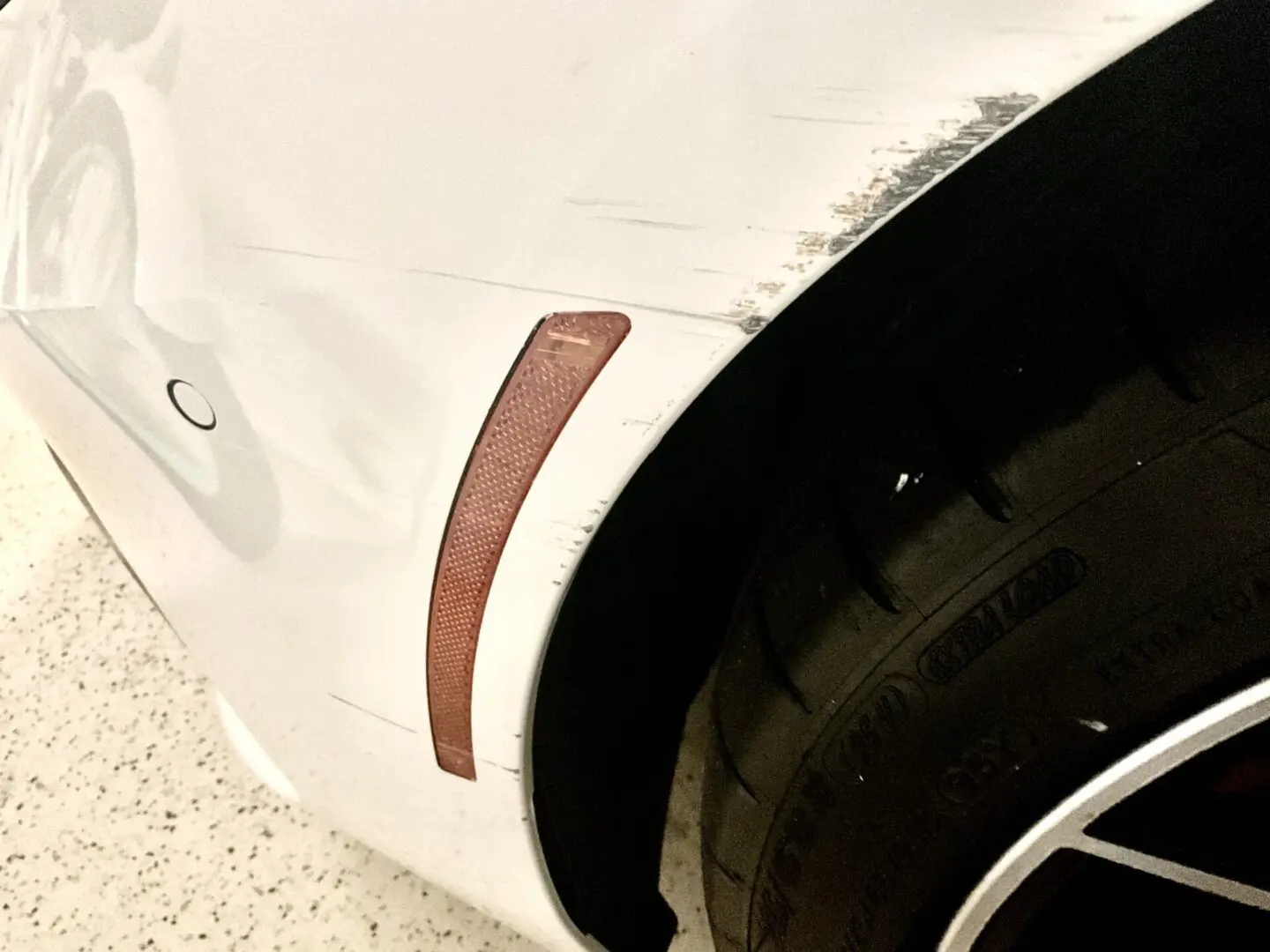 Scratched white car with visible tire.