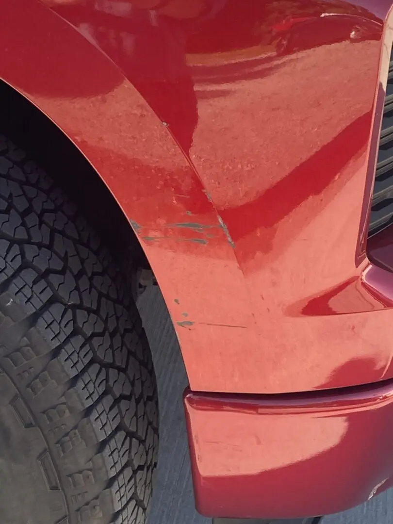 Red car fender with visible scratches.