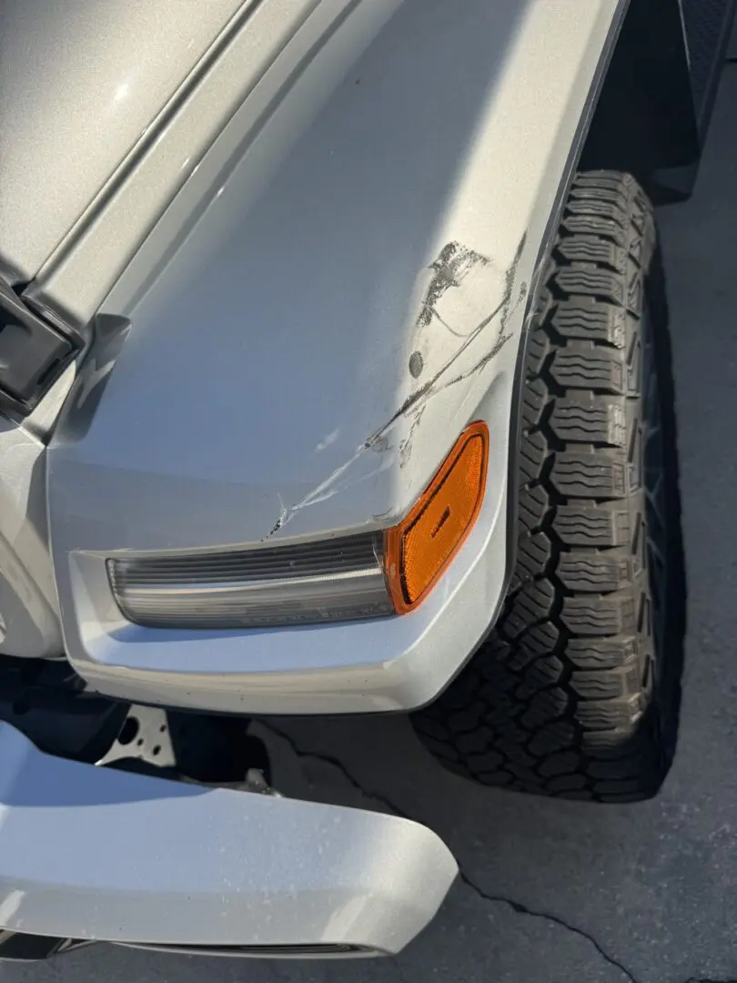 Damaged front corner of a white vehicle.