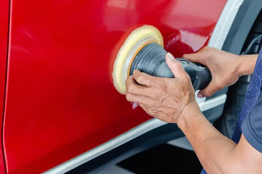 Polishing a red car with buffer tool.