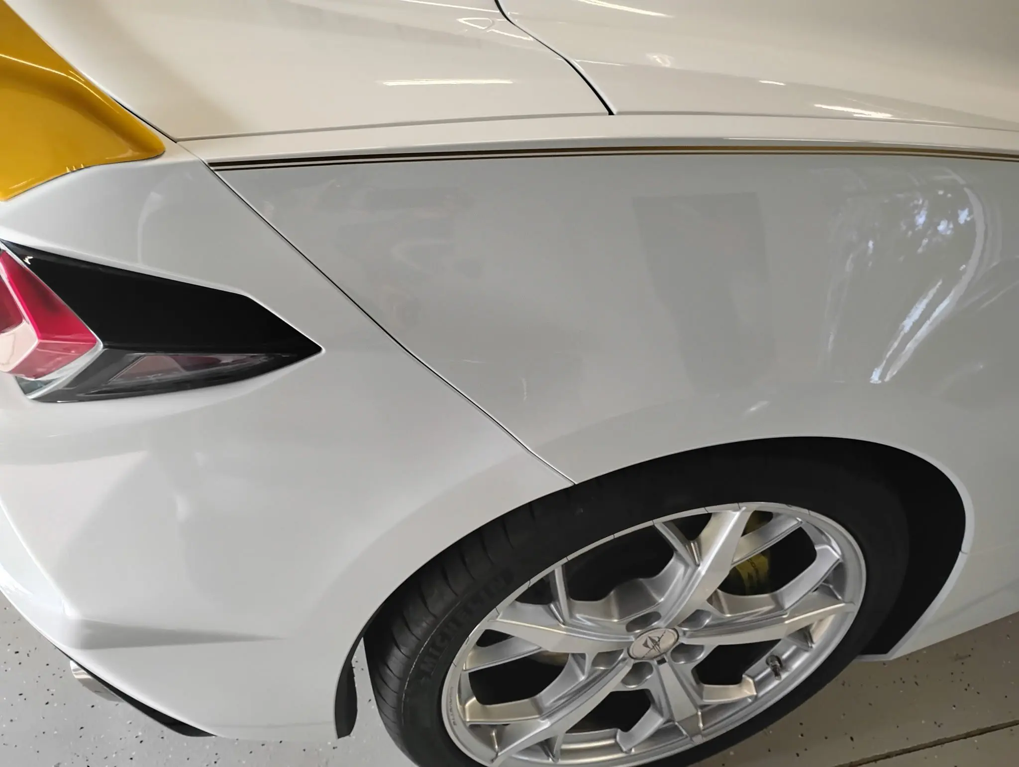 Close-up of a white car's front wheel and fender with a sleek design.