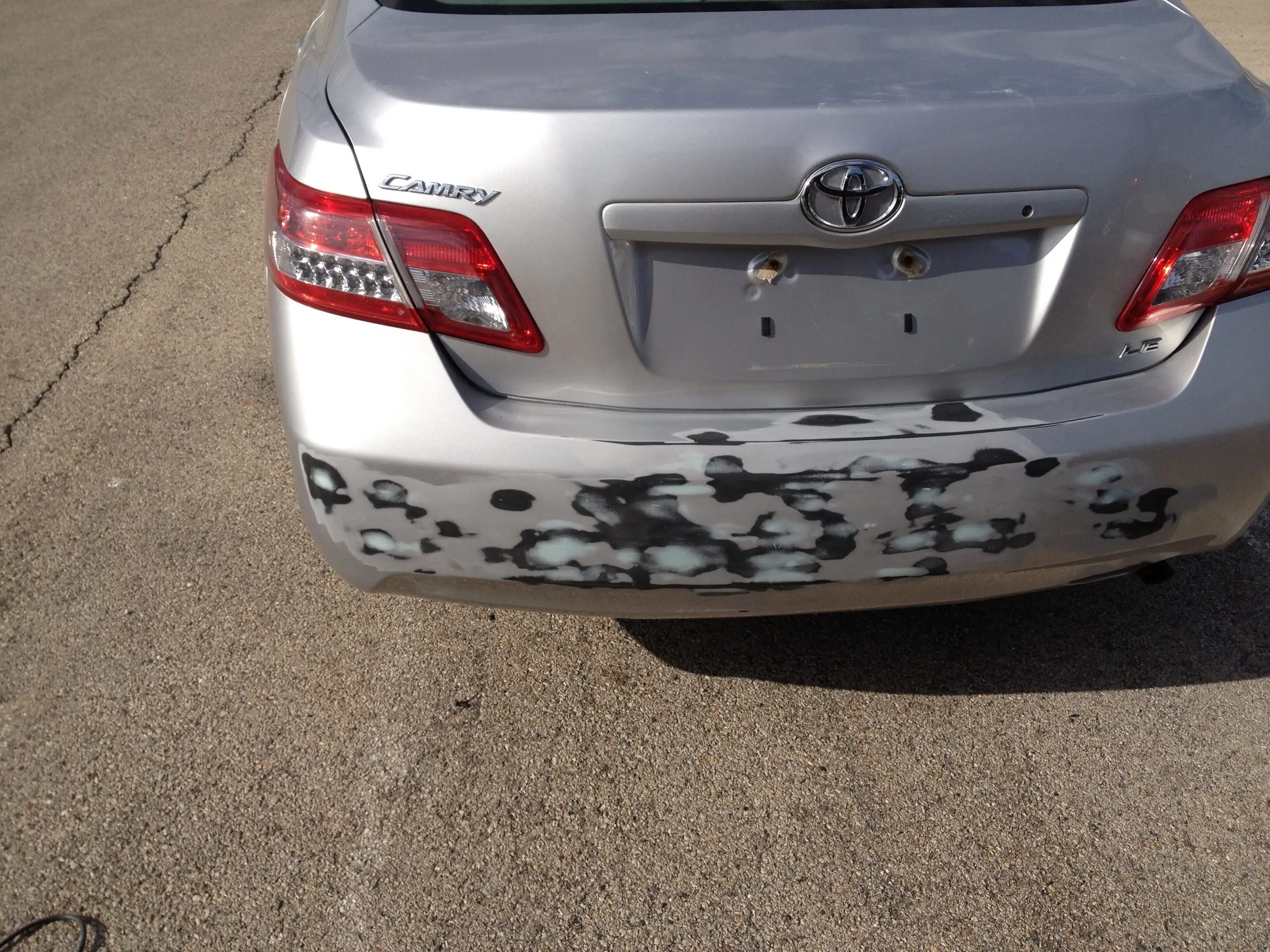 Rear of a silver Toyota car with noticeable bumper damage and missing license plate.