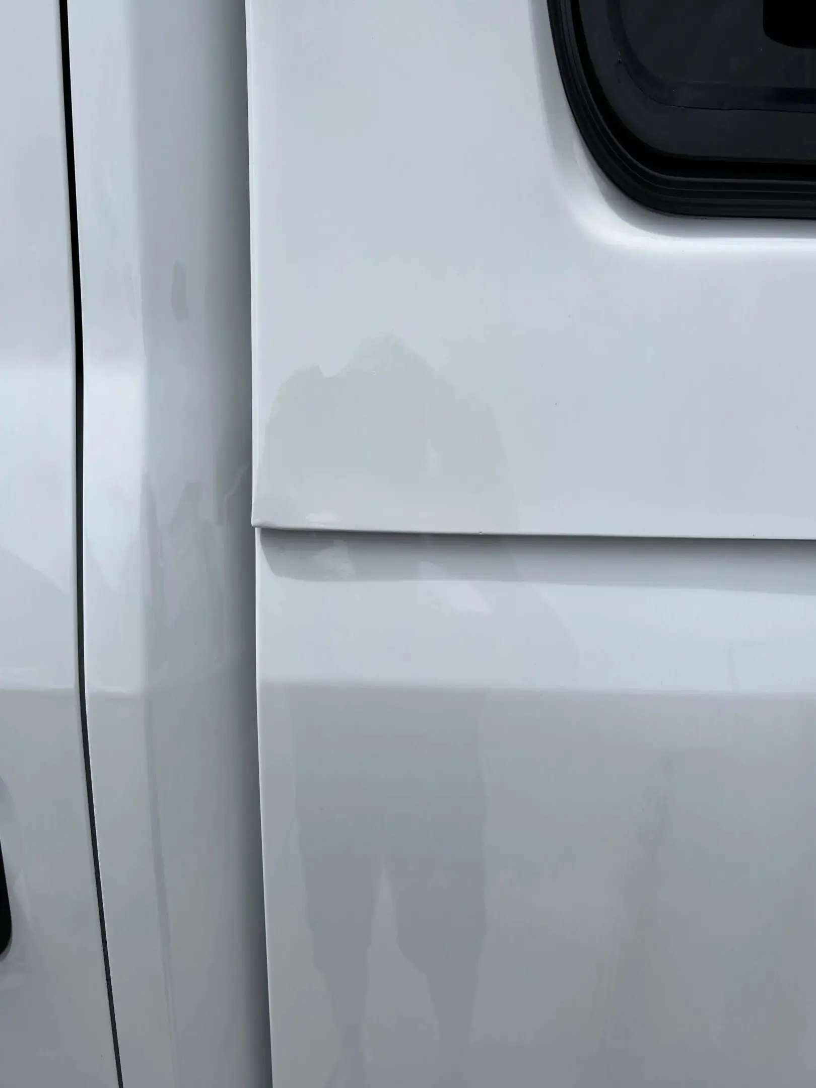 Close-up of a white vehicle door with paint imperfections.