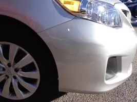 Silver car front with headlight and wheel.