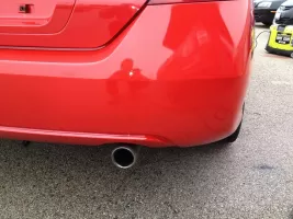 Red car rear bumper with exhaust pipe.