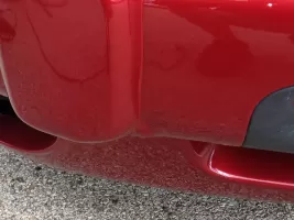 Red car bumper with road reflection.