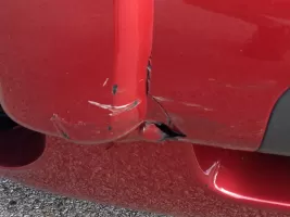 Damaged red car bumper with scratches.