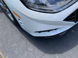 White car front bumper with minor damage.