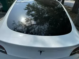 White Tesla car with reflective rear window.