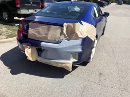 Car with paper-covered rear bumper repairs.