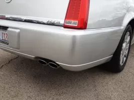 Silver car rear bumper with dual exhaust.